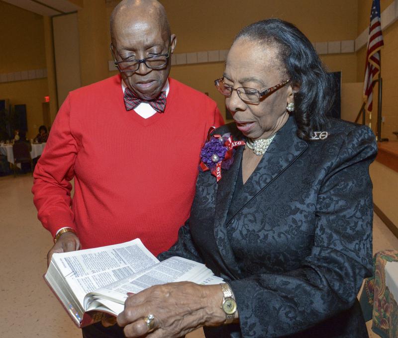 Diaz Bonville, left, and Dr. Reba Ross Hollingsworth look over a bible showing original text, that has mostly been deleted in current bibles, showing references to ethnicity.